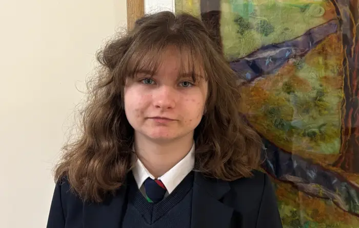 Greta standing in front of a painting in her school uniform