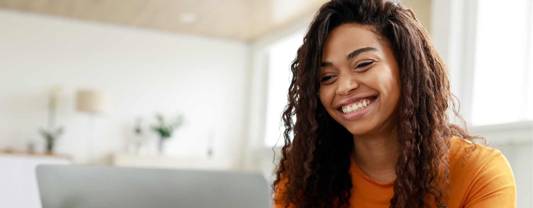 Woman smiling and using laptop at her table